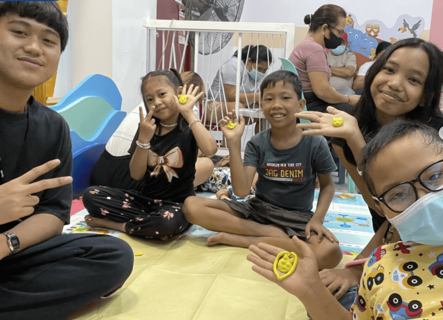 Children smiling and showing clay hearts during a Little Ark activity