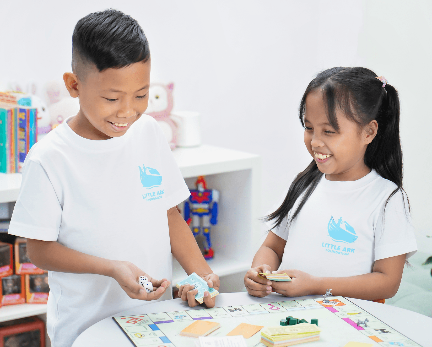 Children smiling while playing a tabletop game at Little Ark