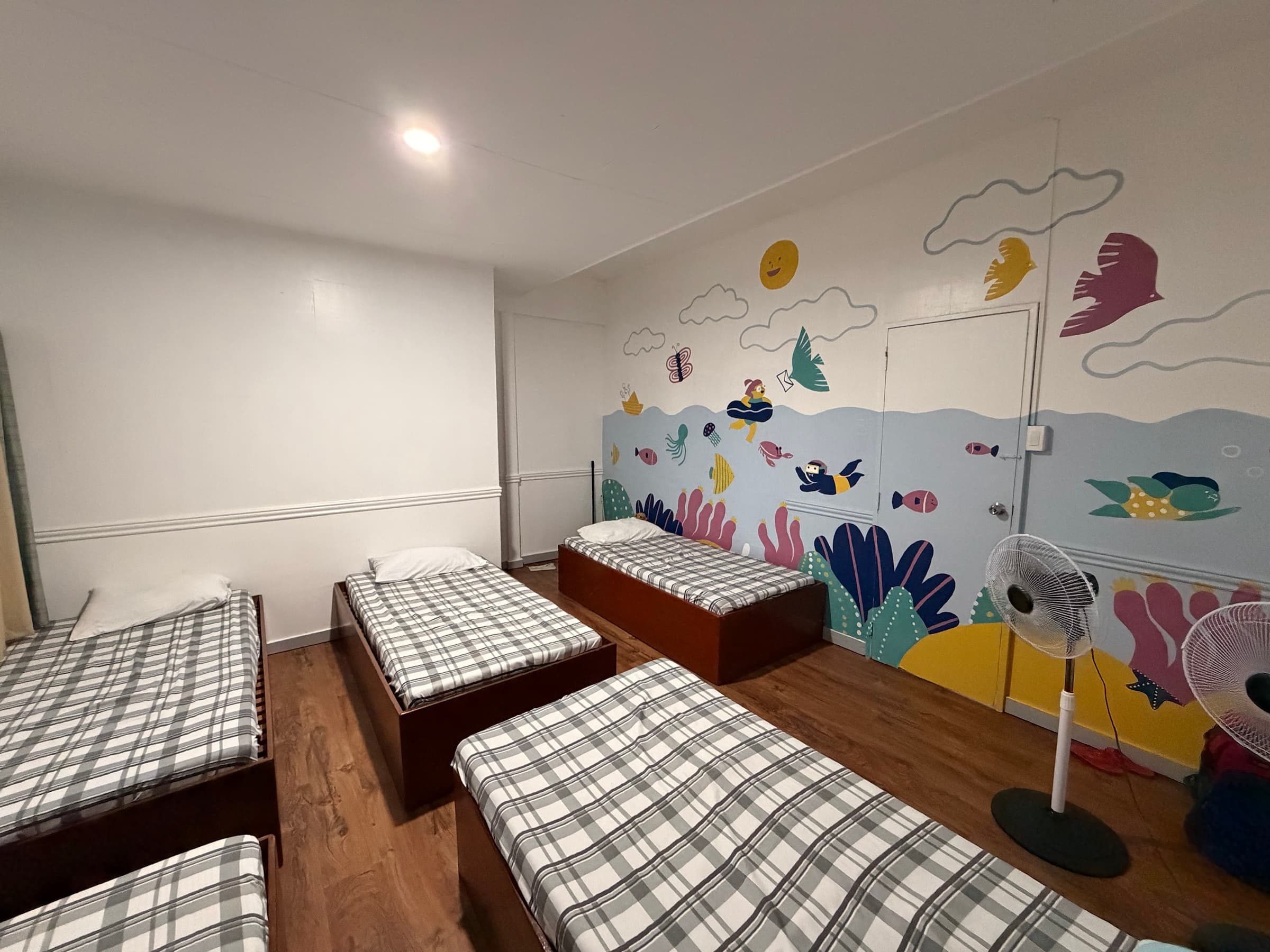 A shared bedroom with multiple beds and an underwater mural inside the Little Ark home