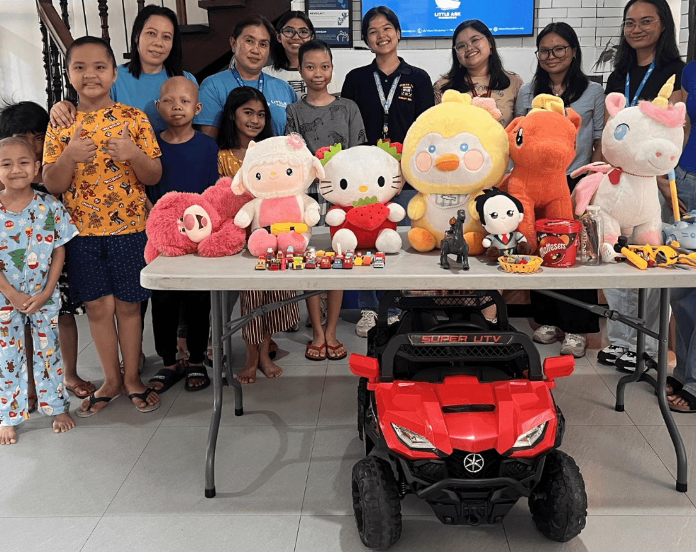 Children, caregivers, and Little Ark team members with donated toys and supplies